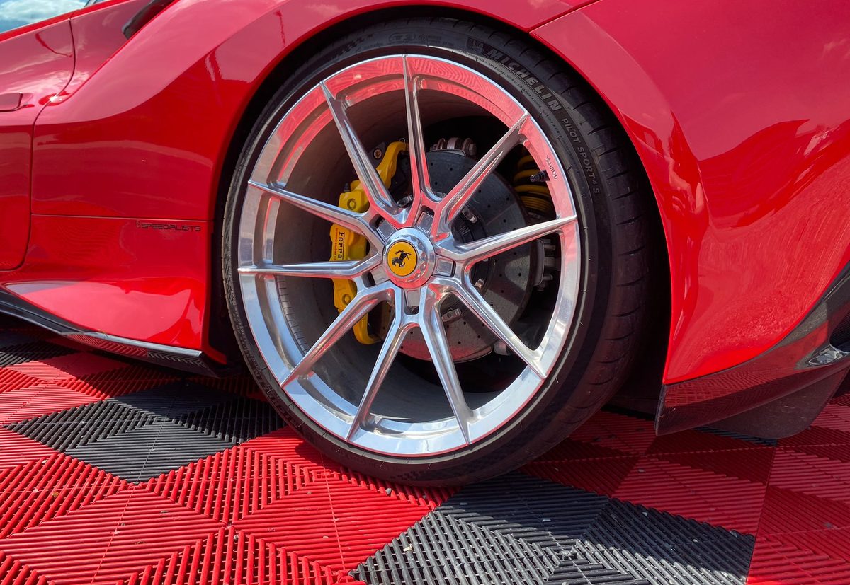 Poliertes Rad eines roten Ferrari mit gelben Bremssätteln nach der Felgenreinigung